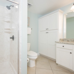 Enjoy a relaxing shower after a day at the beach in this guest bath with stylish cabinetry and spacious vanity