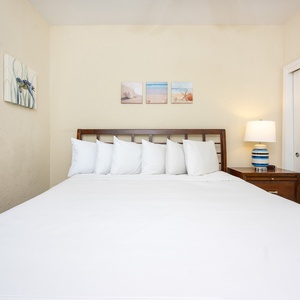 Bright and inviting guest bedroom featuring a king bed with plush pillows and beach-themed artwork for a relaxing getaway