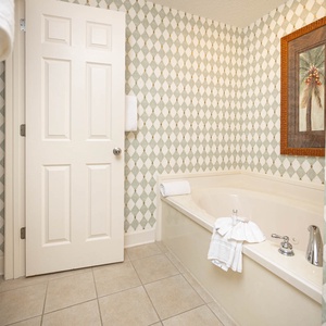 Indulge in relaxation with a spacious jetted bathtub, elegant decor, and fresh towels ready for your comfort