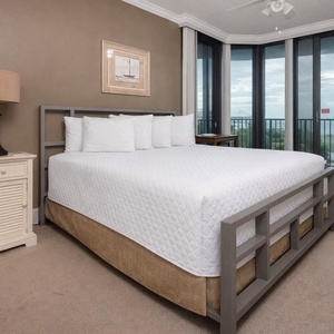 Guest bedroom featuring a plush king bed and large windows offering a serene view of the surrounding landscape