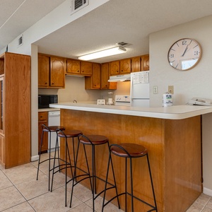 The kitchen features wooden cabinetry, white appliances, and a breakfast bar perfect for casual dining