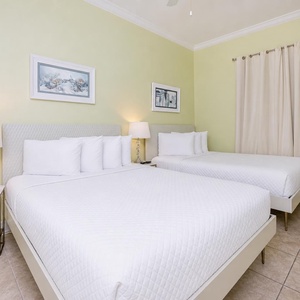 Experience comfort in this guest bedroom featuring two queen beds, soft linens, and cheerful coastal decor
