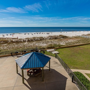 The view showcases a serene beach scene with white sand, lounge chairs, and a gazebo overlooking the tranquil waters
