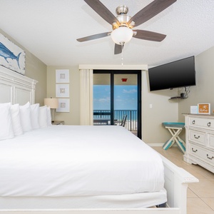 Master suite featuring a king bed, a TV, and a balcony with a view of the gulf and inviting outdoor seating