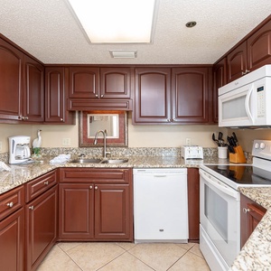 Rich mahogany cabinets and granite countertops enhance this kitchen, featuring a convenient breakfast bar