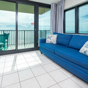 Unwind on the blue sofa with queen sleeper while enjoying panoramic beach views from the corner balcony