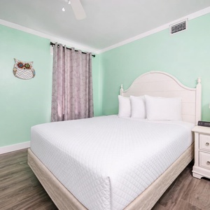 Plush queen bed in the guest suite invites peaceful rest surrounded by calming mint walls