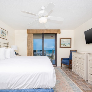 Spacious master suite with a large king bed, coastal decor, and a balcony with beach views