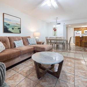 Cozy living area features a plush sofa with queen sleeper, a stylish coffee table, and a dining space in the background