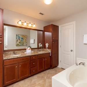The master bath features wood cabinets, a spacious vanity with dual sinks, and a relaxing jetted tub for a serene experience