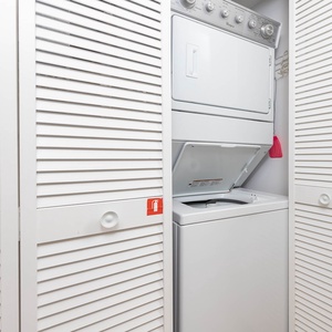 The laundry area features a stacked washer and dryer behind white louvered doors, providing convenient in-unit laundry access