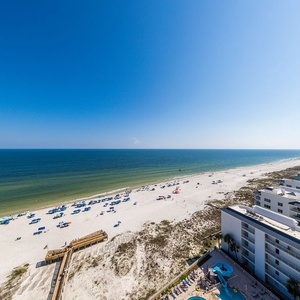 Feel gulf breezes and watch the shoreline, sunshades, and pool area below