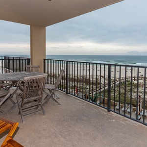 The balcony features a wooden dining set with a beach view, perfect for enjoying meals outdoors in a serene setting