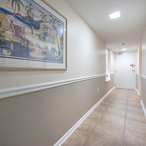 Welcoming hallway features decorative art, tile flooring, and natural light streaming through a window, enhancing the vibe