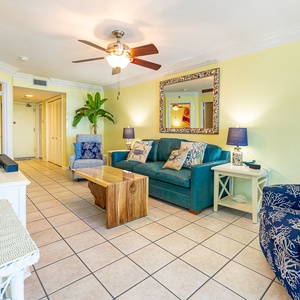Brightly colored seating with ocean decor and a queen sleeper invites relaxation in this living area with a view of the beach