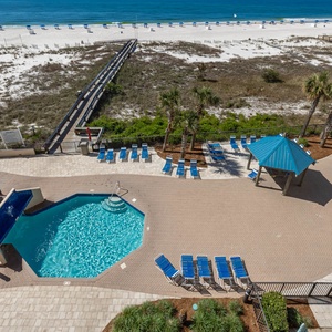 Relax by the pool, surrounded by lounge chairs and palm trees, with easy access to the beach just steps away