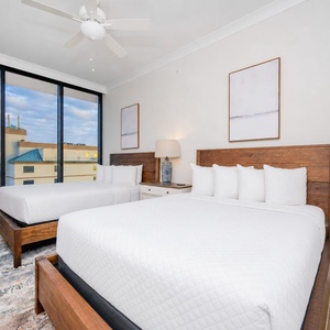 Relax in this guest bedroom with two queen beds, a stylish lamp, and expansive windows offering lovely views