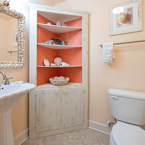 Charming additional half bath featuring a shell-framed mirror, colorful decor, and a unique shell display