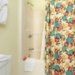 A colorful floral shower curtain complements the guest bathroom, featuring a tub/shower combo and neatly stacked towels