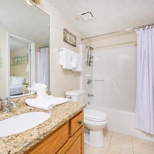 Granite countertops complement the bright bathroom, featuring a tub/shower combo and fresh towels neatly arranged