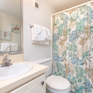 This bathroom features a clean design with a colorful coral-patterned shower curtain and fresh towels for a refreshing stay