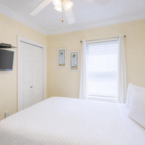 Cozy guest space a queen bed, wall-mounted TV, and shared bathroom space, creating a relaxed atmosphere
