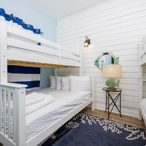 Guest bunk room with a twin bunk bed and a twin over full bunk with a trundle, featuring playful fish decor and a cozy rug