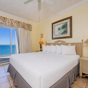 King bed in the master suite offers restful comfort with calm lamps and a balcony view of the sparkling coast