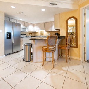 Modern kitchen area features a breakfast bar with seating, granite countertops, and stylish lighting
