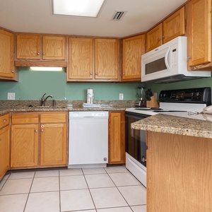 The kitchen features light wood cabinetry, granite countertops, and white appliances