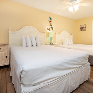 Cheerful guest bedroom featuring two comfortable queen beds, a charming nightstand, and vibrant coastal decor