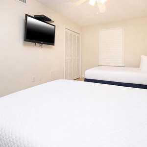 Cozy guest bedroom featuring two double beds, a TV, and a restful vibe