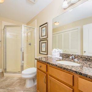 The extra bath features elegant granite countertops, a glass walk-in shower, and laundry area with a washer and dryer