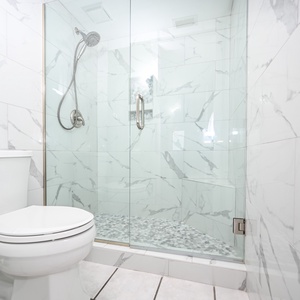 The master bathroom features a sleek walk-in shower with elegant marbled tiles and a modern toilet for a refreshing vibe
