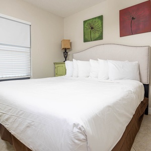 Experience comfort in this inviting guest bedroom with a plush king bed, decorative art, and warm lighting for a restful stay