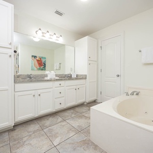 The master bathroom features a relaxing jetted tub, dual sinks, granite countertops, and a glass walk-in shower
