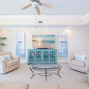 Bright living area featuring a large TV, coastal artwork, and comfortable seating for relaxation and entertainment