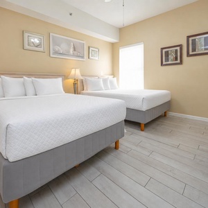 This cozy guest bedroom features two comfortable full beds, soft lighting, and a TV for relaxing evenings