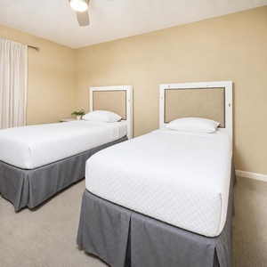 Bright guest bedroom featuring two twin beds with stylish headboards and a cozy atmosphere, perfect for restful nights