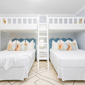 Relax in this guest bunk room featuring two queen beds, a cozy loft with two twins, and a cheerful coastal vibe
