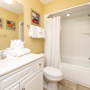 Calming guest bathroom featuring a clean tub/shower combo, fresh towels, and colorful artwork on the walls