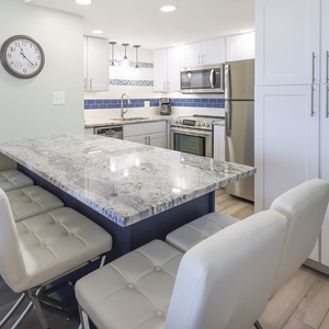 This modern kitchen features sleek cabinetry, stainless appliances, and a spacious granite island perfect for gathering