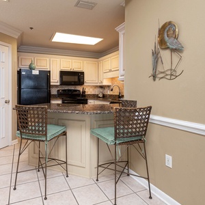 Kitchen area features a granite breakfast bar with stylish seating, complemented by light cabinetry and decorative accents