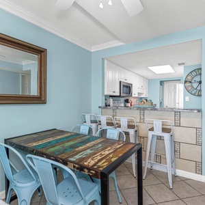 Inviting dining area featuring a rustic table and modern bar stools against a cheerful blue backdrop