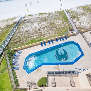 The vibrant pool area features lounge chairs and a playful splash pad, with easy access to the beach just beyond