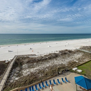 Expansive beach front view showcasing white sand, gentle waves, and lounge chairs along the shore for a relaxing getaway