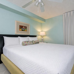 Enjoy a restful night in this serene bedroom featuring a plush king bed, soft lighting, and calming teal walls