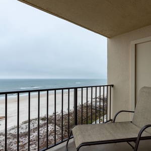 Relax on the balcony chair while enjoying breathtaking views of the sandy beach and tranquil waters just steps away