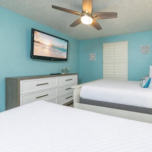 Blue walls surround the guest suite with two beds inviting restful sleep after a busy day