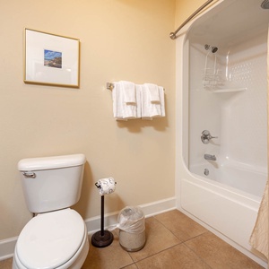This bathroom features a clean design with a shower-tub combo, fresh towels, and a decorative framed picture